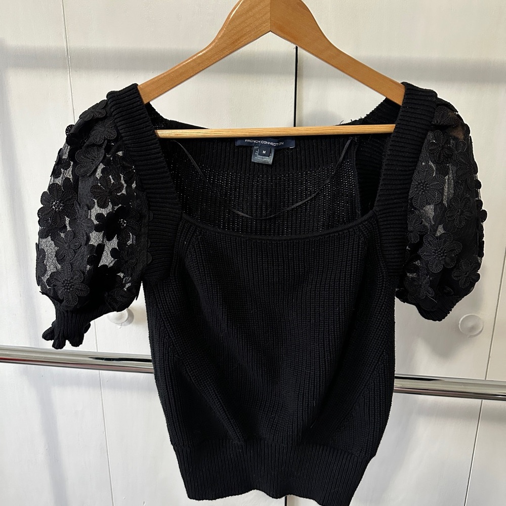Black sweater with sheer puff sleeves.